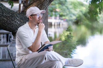 man sits under a tree with a book in his lap