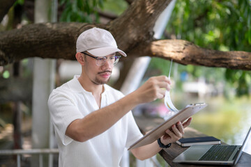 man wearing a white shirt and hat is looking at a piece of paper