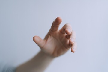 Close-up of human hand reaching out with fingers extended against plain background.