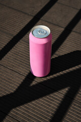 Pink soda can mockup on dark wooden floor with dramatic shadows. Concept of drink packaging,...
