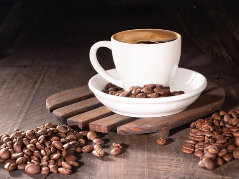 Coffee cup with froth surrounded by rich coffee beans for a cozy vibe