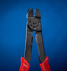 Professional electrical cable crimping pliers on vibrant blue gradient background