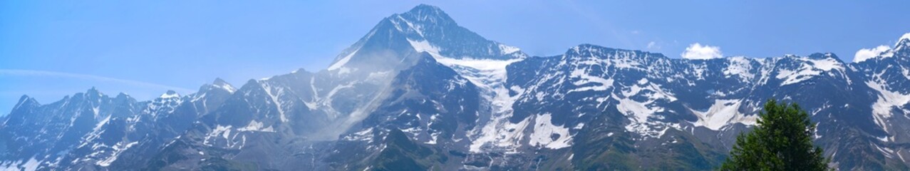 Wide angle view of mountain panorama with rockfall and dust with mountain peaks Kleines Nesthorn...