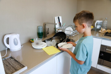 Boy Cleaning Dishes in Kitchen at Sink