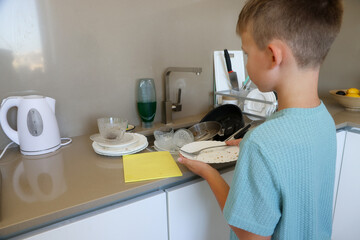 Boy Holding Dirty Plates in Kitchen Near Sink