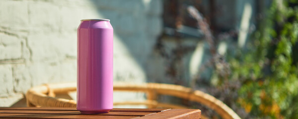 Pink soda can mockup on light wooden table in warm lighting. Concept of drink packaging, branding...