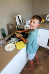 Smiling Boy Washing Dishes at Sink