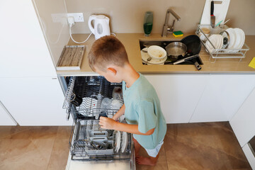 Child Loads Dishwasher in Kitchen