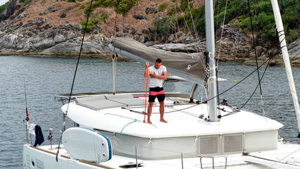Morning on a yacht. Fitness exercises on the roof of a catamaran. A man doing exercises during a...