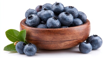 Fresh blueberries glistening with water droplets artfully arranged in a wooden bowl against white.