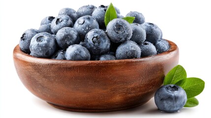 A wooden bowl filled with fresh blueberries, adorned with water droplets and a vibrant green leaf.