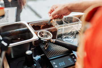 Close-up of a barista scooping fresh ground coffee into a portafilter, preparing to make an...