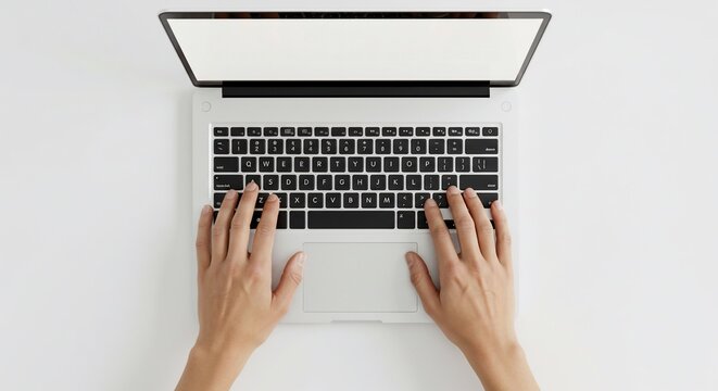Overhead view of hands typing on a modern laptop with a blank white screen
