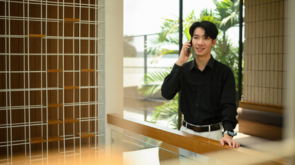 A Young professional enjoying a relaxed phone call in a stylish, sunlit interior office space
