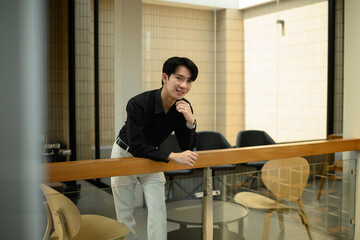 A Cheerful Asian man in a smart outfit enjoying a relaxed moment in a contemporary lounge area