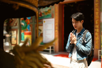 A young Asian man respectfully greets at a spiritual site at the Chinese temple
