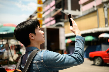 A Young tourist captures street scenes while exploring a busy urban street at Chiangmai, Thailand