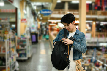 A young traveler opens his backpack inside a lively indoor market, checking for essentials. Please...