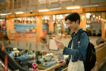 Casual traveler holds a phone while enjoying a shopping trip in a lively local market center