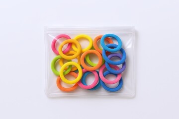 Colorful rubber bands in a small clear plastic bag on a white background.