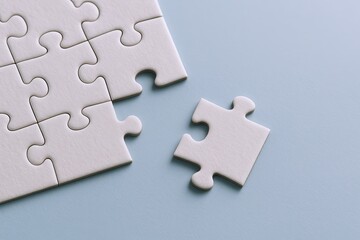 Fototapeta premium Close-up of a white puzzle with one piece missing on a flat light gray surface.