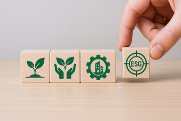 Hand placing wooden block with ESG symbol on a row of eco and sustainability themed blocks.