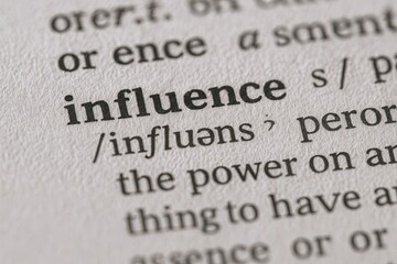 Obraz premium Close-up of a dictionary page showing the word influence with pronunciation and definition.