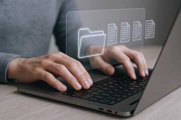 Close up of hands typing on laptop with digital file folder icons on transparent screen.