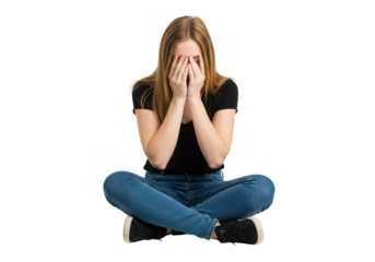 A young woman sits crosslegged with her hands covering her face, expressing distress and sadness isolated on transparent background