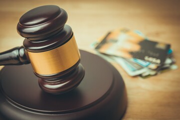 Wooden judge hammer gavel with many credit cards in courtroom. Credit card debt trial judgement, personal financial problem, financial laws regulation, consumer protection and so on concept.