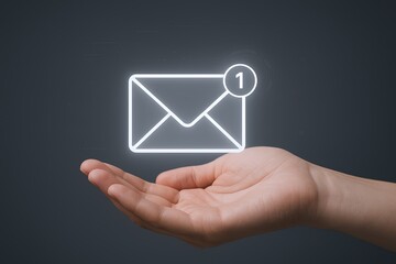 Digital communication concept showing email notification icon floating above hand against dark background.