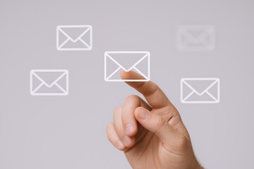 Hand reaching out to touch floating email icons in a digital communication concept.