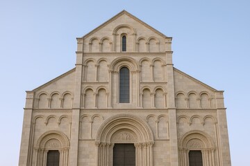 Fototapeta premium Ancient stone church with detailed Romanesque architecture and arched windows.