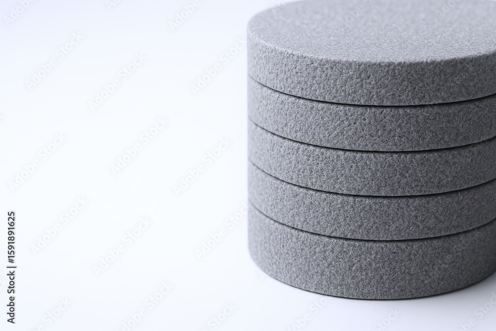 Poster multiple gray round foam cushions stacked vertically on a plain white background.