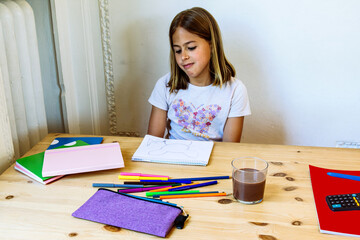 Elementary school student drawing at home with colored pencils and notebooks