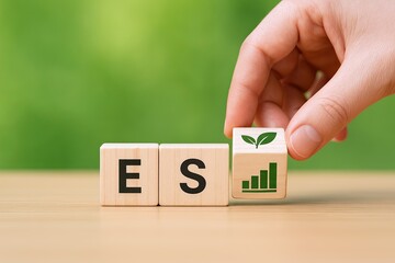 Hand placing wooden block with growing plant icon on top of bar chart symbol beside letter blocks ESP.