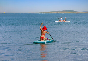 young women in red bikini  riding  on sup surfing in the sea at sumer time