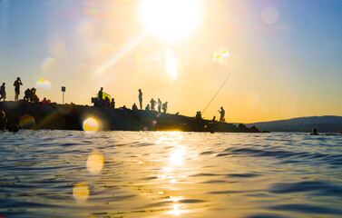 Beach with many people on the seashore at beautiful sunset on a summer evening. Silhouettes