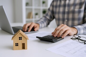 Fototapeta premium Person Calculating House Expenses Using Calculator at Desk with House Model and Documents.