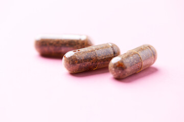 Siberian ginseng (Eleutherococcus senticosus) capsules on bright background. Soft focus. Close up. Copy space	