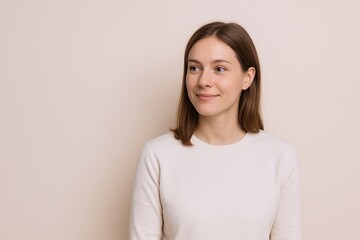 Obraz premium Friendly young woman with shoulder-length brown hair and casual white top posing indoors.