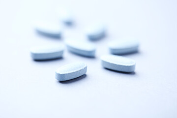 Multivitamin tablets on bright paper background. Close up. Copy space	
