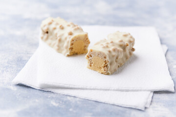Protein bar in two pieces on wooden background. Soft focus. Close up. Copy space	