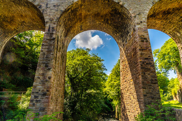 Naklejka premium A view through the arches of a viaduct in the Torrs Riverside Park at New Mills, High Peak in the UK in summertime