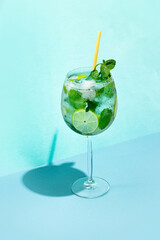 Hugo Spritz cocktail with mint, lime and ice on blue pastel background. Concept of summer spritz...