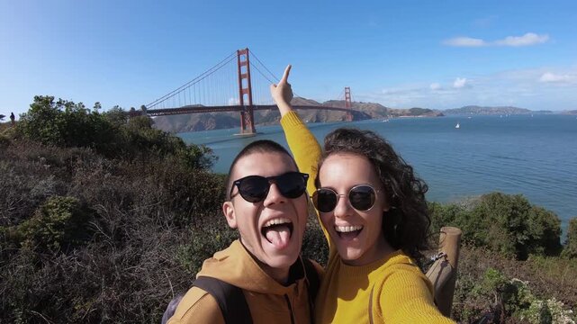 Smiling hike couple taking selfie with panoramic view of Golden Gate Bridge in San Francisco