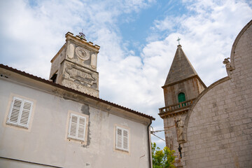 A detailed view of a historic stone clock tower dated 1889 alongside a church steeple in the old...
