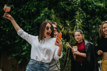 Four friends sharing a joyful moment outdoors, celebrating with drinks and vibrant energy,...