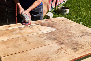 Sanding wooden surface with abrasive disc on angle grinder, power tool smoothing tabletop in...