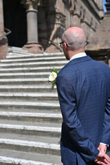Groom waiting at the steps of a town hall for bride